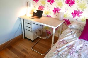 een bureau met een laptop naast een bed bij Anna's House in Ickleford