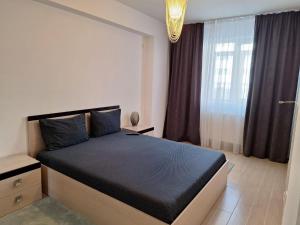 - une chambre avec un grand lit noir et une fenêtre dans l'établissement Cazare Apartament 2 camere, à Chiajna