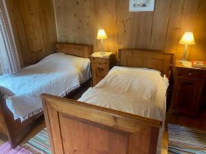 two beds in a room with two lamps on tables at Bondo Bergell in Promontogno