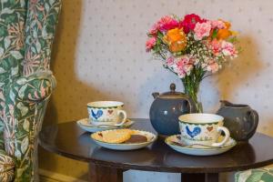 una mesa con dos tazas y un jarrón con flores en Marshwood Farm B&B and Shepherds Hut, en Dinton