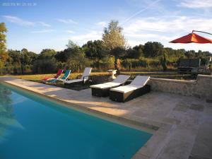 a swimming pool with lounge chairs and an umbrella at le mas de lombreyra in Massugas