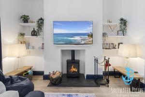 uma sala de estar com lareira e uma televisão de ecrã plano em Harbour Townhouse em Brixham