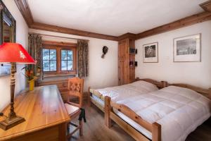 1 dormitorio con 1 cama y escritorio con lámpara en Résidence Agathe Blanche - Chalets pour 12 Personnes 984, en Courchevel