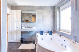 a bathroom with a tub and a sink and a window at Stijlvolle @ luxe vrijstaande woning Maastricht in Eijsden +28 photos