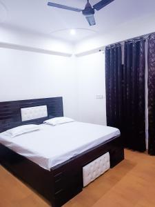 sypialnia z łóżkiem i wentylatorem sufitowym w obiekcie Hotel Satguru Indrapuram, Shaktikhand w mieście Ghaziabad