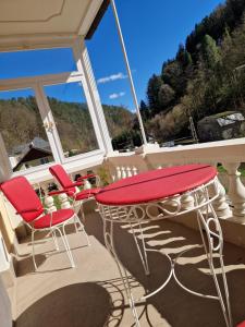 a patio with red chairs and a table on a porch at Pension Villa Anna in Bad Schandau +43 photos