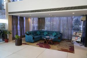 sala de estar con sofá azul y mesa en Hotel Clarks Collection Bhavnagar, en Bhavnagar