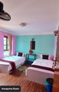 two beds in a room with pink and blue walls at Annapurna Guest House and Rooftop Restaurant in Bhaktapur