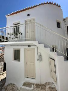 a white house with stairs and a balcony at Lythi Kythnos in Kithnos