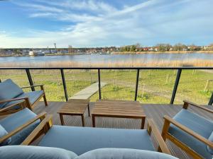 a balcony with chairs and tables and a view of a river at Ostseeperle in Dziwnów