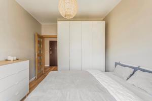 ein Schlafzimmer mit einem weißen Bett und einem Schrank in der Unterkunft Gandalf House in Warschau