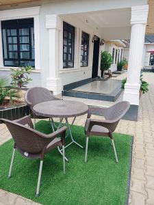 a patio with a table and chairs on grass at Cacecy Luxury Homes 2 -Bedroom in Bungoma
