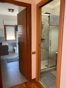 La salle de bains est pourvue d'une douche et d'une porte en verre. dans l'établissement Appartamento ad Acilia, à Acilia