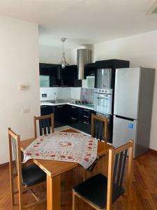 La cuisine est équipée d'une table, de chaises et d'un réfrigérateur. dans l'établissement Appartamento ad Acilia, à Acilia