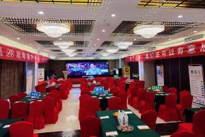 a room with red chairs and tables and a screen at Ramada Linyi North in Linyi
