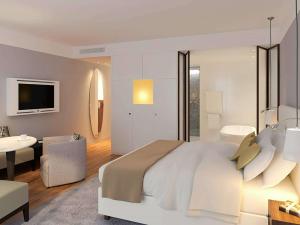 パリにあるソフィテル パリ アルク ドゥ トリオンフのベッドルーム(大型ベッド1台付)、リビングルームが備わります。