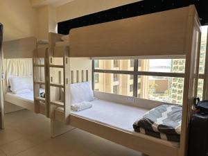 2 stapelbedden in een kamer met een raam bij Bollywood Beach Hostel in Dubai