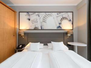 فندق ميركور ميونيخ شفابينغ في ميونخ: سرير ابيض كبير وعليه صورة كبيرة
