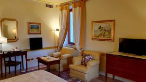 a living room with a television and a couch and a chair at Resort Locanda San Verolo Boutique Hotel in Costermano sul Garda