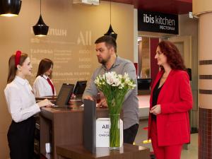 ibis Sibir Omsk Hotel في أومسك: مجموعة من الناس تقف حول مكتب الاستقبال