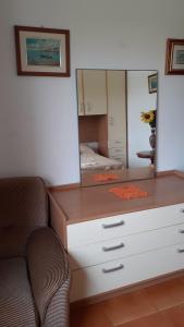 komodę z lustrem i krzesłem w pokoju w obiekcie Affittacamere Tortolì w mieście Tortolì