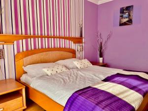 um quarto com uma cama grande e paredes roxas em Villa Lux em Hévíz