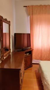 sypialnia z komodą z telewizorem i lustrem w obiekcie Affittacamere Tortolì w mieście Tortolì