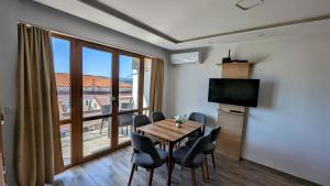 a dining room with a table and chairs and a large window at Apartment DEVA in Balchik