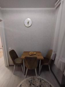 mesa de comedor con sillas y reloj en la pared en Balti Apartment, en Bălţi