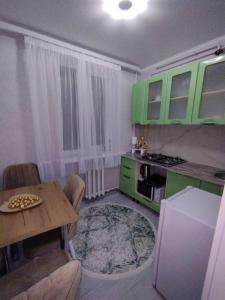 cocina con armarios verdes, mesa, mesa y sillas en Balti Apartment, en Bălţi