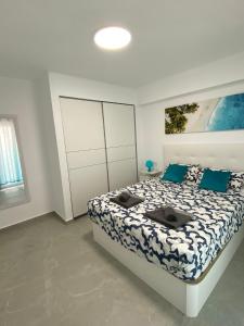 1 dormitorio con 1 cama grande con almohadas azules en Apartamento VI-DA PLAYA en Puerto de Sagunto