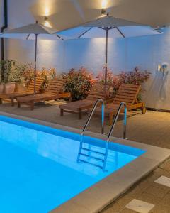 una piscina con bancos y sombrillas en un edificio en Goldberg Apartments Osijek, en Osijek