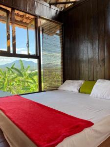 ein Schlafzimmer mit einem Bett mit einer roten Decke darauf in der Unterkunft Kubu Yr in Jembrana