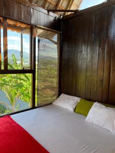 Bett in einem Zimmer mit einem großen Fenster in der Unterkunft Kubu Yr in Jembrana