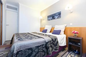 a hotel room with a bed and a table with flowers on it at Aparthotel Chez Adagio Paris La Défense-2P with Terrace in Courbevoie
