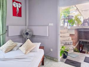 a bedroom with a white bed and a fan at The Brick House Kandy in Kandy