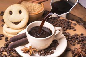 a cup of coffee sitting on a table with coffee beans at LD Guest House in Ayodhya