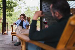 una mujer sentada en un porche con una copa de vino en Oasyhotel, en Limestre