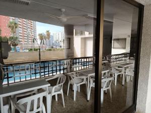 a restaurant with white tables and chairs and a window at Pueblo Español in Cullera