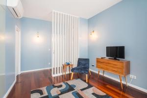 ein Wohnzimmer mit einem TV und einem Stuhl in der Unterkunft Victoria Project - Apartments - Private Parking in Porto