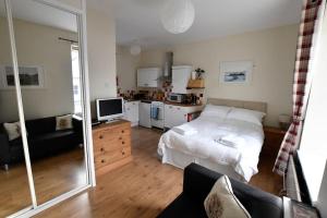 a bedroom with a white bed and a kitchen at Argyll House Pennyghael in Salen