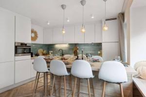 une cuisine avec une table et quatre chaises blanches dans l'établissement Raphaelle - trendy appartement met 2 slaapkamers, à Ostende 11 autres photos