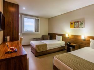 um quarto de hotel com duas camas e uma secretária em Ibis Styles Belém Hangar em Belém