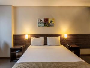 a bedroom with a large bed with two night stands at Ibis Styles Belém Hangar in Belém