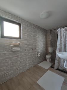 a bathroom with a sink and a toilet and a window at Sobe RoomsBella in Ripač