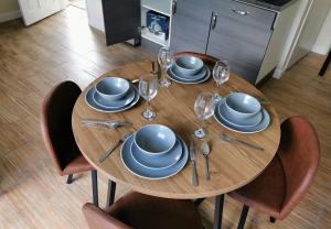 a wooden table with blue dishes and wine glasses at Stunning 3 Bedroom 5 beds House in Wolverhampton in Wolverhampton