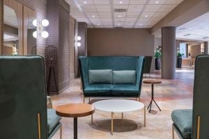 una sala de espera con un sofá verde y mesas en Hilton Garden Inn Bologna North en Bolonia