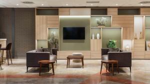 a lobby with couches and a flat screen tv at Hilton Garden Inn Bologna North in Bologna