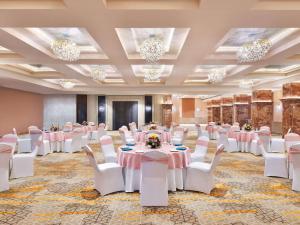 um salão de banquetes com mesas, cadeiras e lustres em Novotel Jodhpur ITI Circle em Jodhpur