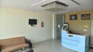 una sala de espera con sofá y TV en Hotel Buddha Vibrant en Deoghar